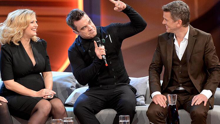 Moderator Markus Lanz (r) unterh&auml;lt sich am 03.11.2012 in der ZDF-Show &laquo;Wetten, dass..?&raquo; in der &Ouml;VB-Arena in Bremen mit seinen G&auml;sten, US-S&auml;nger Robbie Williams und der schwangeren Moderatorin Barbara Sch&ouml;neberger. Foto: Sascha Baumann/ZDF/dpa