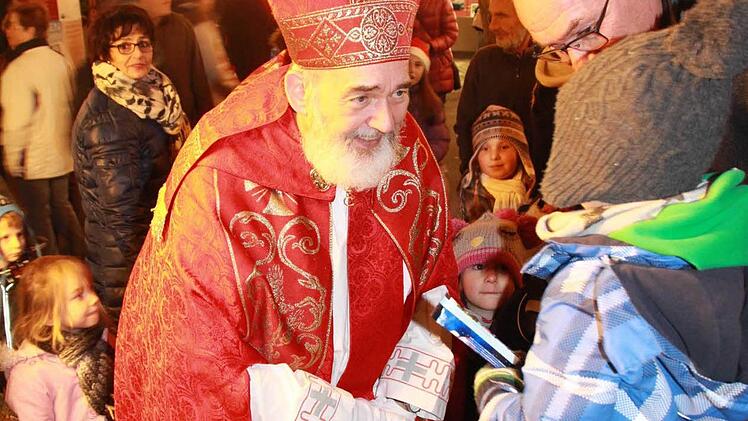 Nikolaus-Darsteller Udo Dickhage verteilt beim Weihnachtsmarkt am Freitagabend Schokolade an die Kinder. Foto: Carmen Schmitt