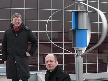 Achim Keppner (links) und Alexander Nordhus vor ihrer Kleinwindkraftanlage im Energiepark Hirschaid. Sie ist eine Kombination aus dem sogenannten Darrieus-Rotor (außen) und der Savonius-Turbine. Foto: Matthias Litzlfelder