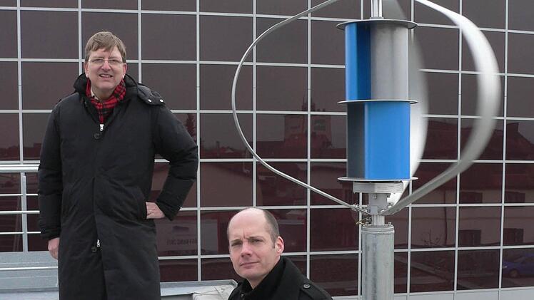 Achim Keppner (links) und Alexander Nordhus vor ihrer Kleinwindkraftanlage im Energiepark Hirschaid. Sie ist eine Kombination aus dem sogenannten Darrieus-Rotor (außen) und der Savonius-Turbine. Foto: Matthias Litzlfelder