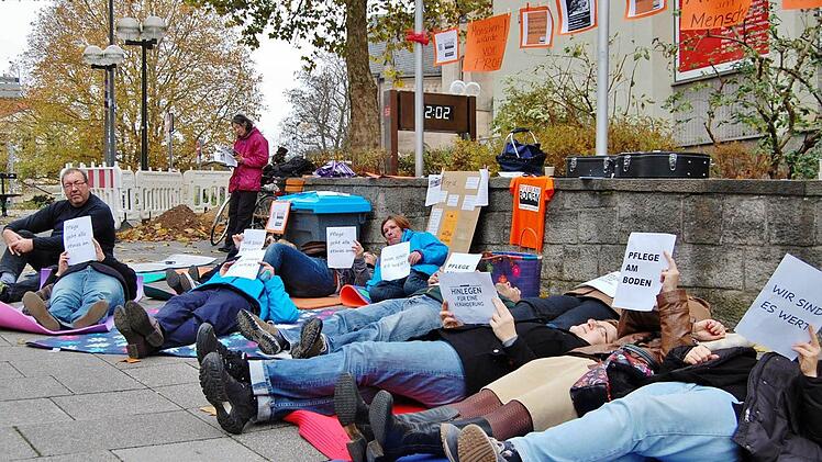 Pflege am Boden: Ein Dutzend Pflegekräfte aus den Landkreisen Bad Kissingen und Rhön-Grabfeld legten sich stellvertretend für alle Kollegen auf den kalten Boden. Fotos: Sigismund von Dobschütz