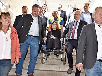 Die Senioren- und Behindertenbeauftragte Christina Flauder machte den Test und ließ sich in einem Rollstuhl von Michael Theurer (rechts) und Ingo Lehmann (links) die Bahnhofstreppe hinuntertragen.