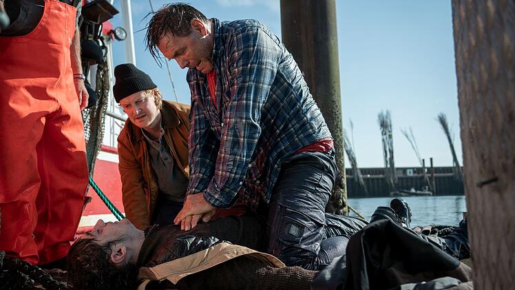 G&ouml;tz Fischer (Max Hopp, rechts) hat seinen Sch&uuml;tzling Hark "Harke" Petersen (Eren Yilmaz, liegend) aus dem Wasser gezogen. Niels Schneider (Leo Meier) will helfen, doch es ist zu sp&auml;t.