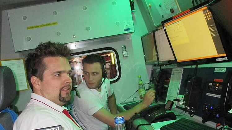 Martin Nickel (links) und Marcel Straub an den Arbeitsplätzen des Einsatzleitwagens 2, der das fahrende Büro des Einsatzleiters ist Foto: BRK