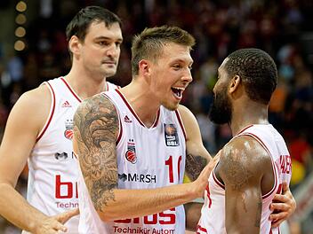 Bambergs Hauptdarsteller Daniel Theis (l.) und Brad Wanamaker feiern den Sieg. Dalibor Bagaric (hinten links) scheint noch nicht ganz in Feierstimmung zu sein. Foto: dpa