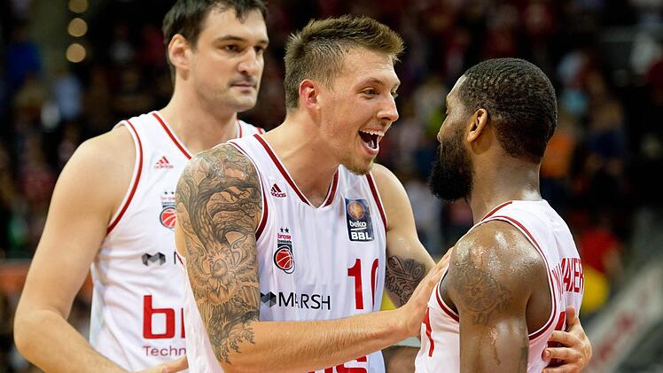 Bambergs Hauptdarsteller Daniel Theis (l.) und Brad Wanamaker feiern den Sieg. Dalibor Bagaric (hinten links) scheint noch nicht ganz in Feierstimmung zu sein. Foto: dpa