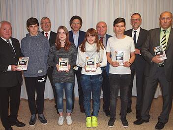Landratstellvertreter Helmut Fischer (links), Walter Partheymüller von der Sparkasse, Schulamtsdirektor Norbert Hauck, Rektor Wolfgang Fischer, Hartmut Büchner (AK SchuleWirtschaft), Hefthersteller Manfred Weber (hinten v. li.) sowie die Schüler Jonas Schramm, Janine Schober, Nina Engel und Gerald Brodkorb (vorne 2. bis 5. v. li.) stellten das Hausaufgabenheft des Arbeitskreises vor.  Foto: Alfred Thieret
