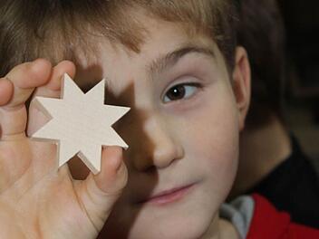 Prüfender Blick: Von einem länglichen Rohling in Form eines Sternes durfte sich jedes Kind ein Stück absägen und seinen eigenen Stern natürlich auch mit nach Hause nehmen. Das freute nicht nur Maurice.Foto: Nina Grötsch