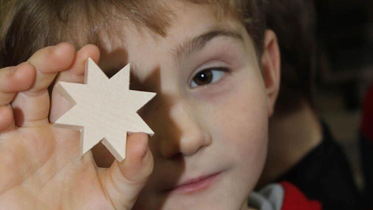 Prüfender Blick: Von einem länglichen Rohling in Form eines Sternes durfte sich jedes Kind ein Stück absägen und seinen eigenen Stern natürlich auch mit nach Hause nehmen. Das freute nicht nur Maurice.Foto: Nina Grötsch