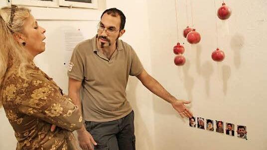 Installation: Künstler Foad Rahnama mit seinem Werk "Dick Tator" und im erklärenden Gespräch mit Vernissagebesucherin Gesine von Postel.