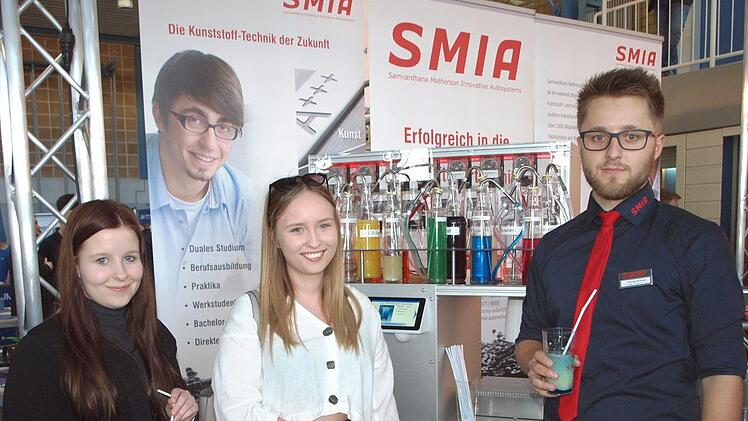 Die beiden jungen Damen lassen sich am SMIA-Stand einen Cocktail aus einem Cocktail-Roboter schmecken, den der duale Student Thomas Kirchner (rechts) entwickelte.