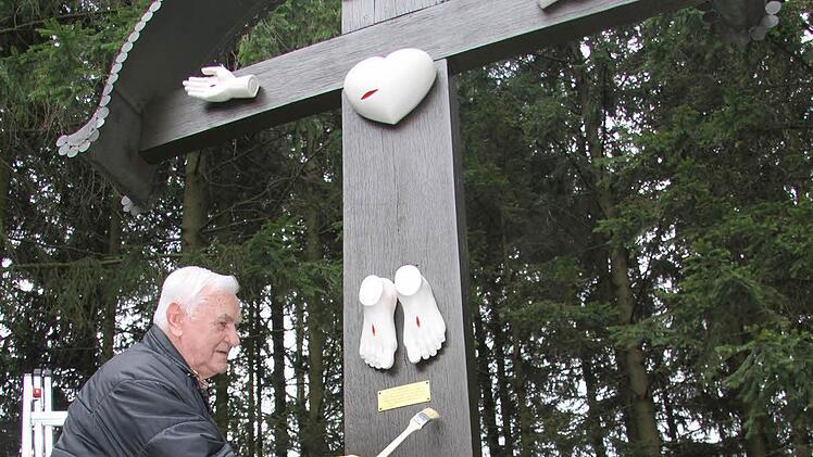 Der Wartenfelser Ludwig Melzer hat seit zwölf Jahren eine Art Patenschaft für das Fünf-Wunden-Kreuz mitten im Wald übernommen. Jetzt hat er es neu gestrichen, denn am Karfreitag spricht Pater Godfryd dort die Sieben Worte Jesu. Foto: Sonja Adam