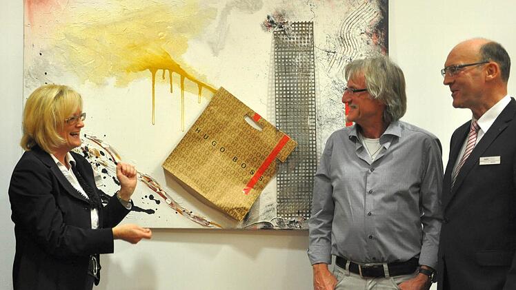 Vernissage in der Bank Schilling: Kulturmanagerin Astrid Hedrich-Scherpf, Künstler Helmuth Marx und Vorstand Matthias Busch (von links) vor dem dreidimensionalen "Hugo Boss Bild", eine sogenannte Assemblage. Foto: Jacqueline Vera Mihm