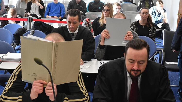 Zwei der sieben Angeklagten verbergen zum Prozessbeginn ihr Gesicht vor den Medienleuten. Foto: Ronald Rinklef