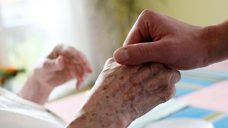 Ein Pfleger hält in einem Pflegeheim die Hand einer Bewohnerin. Oft bilden die Pflegekräfte eine Ersatzfamilie für den Betreuten. Symbolfoto: Oliver Berg/dpa