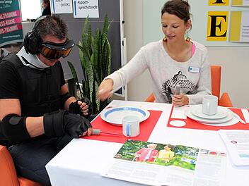 Nico Müller versucht Besteckin der Hand zu halten - mit Handschuhen, die Alterszittern simulieren.