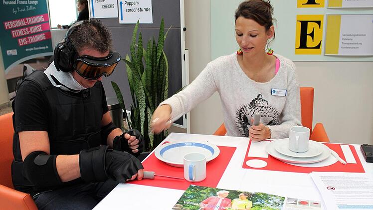 Nico Müller versucht Besteckin der Hand zu halten - mit Handschuhen, die Alterszittern simulieren.