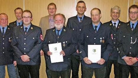 Feuerwehr-Führungskräfte, Vorstandsmitglieder und Ehrengäste flankieren die Jubilare Franz Scheckenbach und Stefan Pechtold (mit Ehrenurkunden).  Foto: Klaus Oelzner