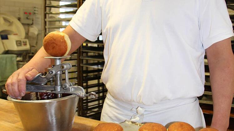 Jürgen Feiler bepudert die Krapfen. Foto: Oliver Schmidt