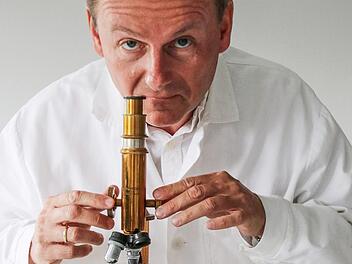 Chemiker Ralph Brückner begutachtet unter dem Mikroskop die winzigen Tröpfchen seiner Beschichtung, die auf Oberflächen eine antibakterielle Wirkung erzielen.  Foto: Sebastian Schanz
