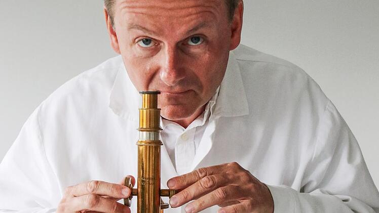 Chemiker Ralph Brückner begutachtet unter dem Mikroskop die winzigen Tröpfchen seiner Beschichtung, die auf Oberflächen eine antibakterielle Wirkung erzielen.  Foto: Sebastian Schanz
