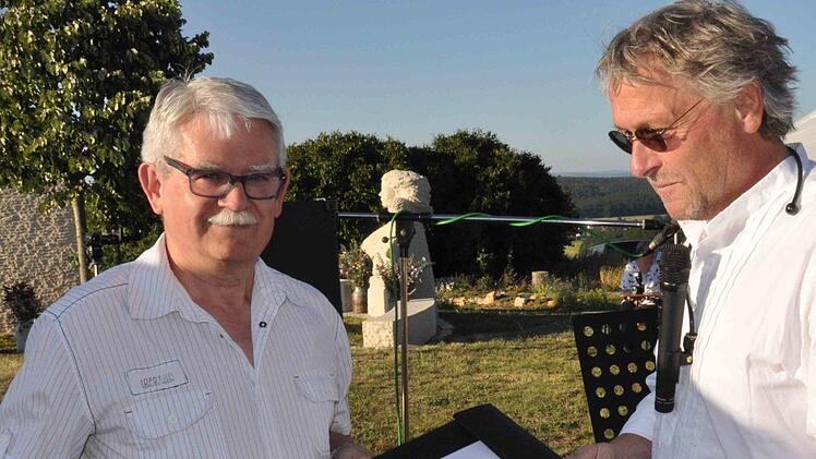 Kirchenpfleger Andreas Kerner (links) erhielt von Bildhauer Clemens Muth zur Erinnerung eine Mappe mit Entwurfsskizzen der Bildstockanlage überreicht. Foto: Mathias H. Walther