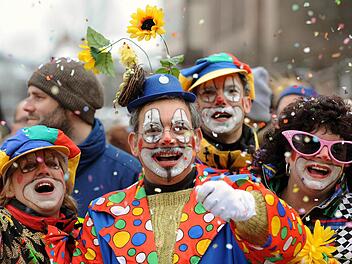 Besucher in Clown-Kostümen werfen mit Konfetti beim Faschingsumzug in Nürnberg . Foto: Tobias Hase/dpa