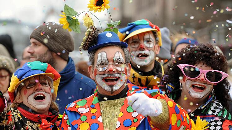 Besucher in Clown-Kostümen werfen mit Konfetti beim Faschingsumzug in Nürnberg . Foto: Tobias Hase/dpa