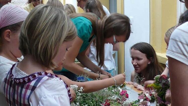 Die Kinder beim Binden eines Blumenkränzchens