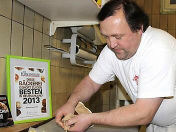 Hubert Ruß beim Backen des Spritzgebäcks. Der Teig wird durch einen Spritzbeutel gedrückt. Foto: Schadeck