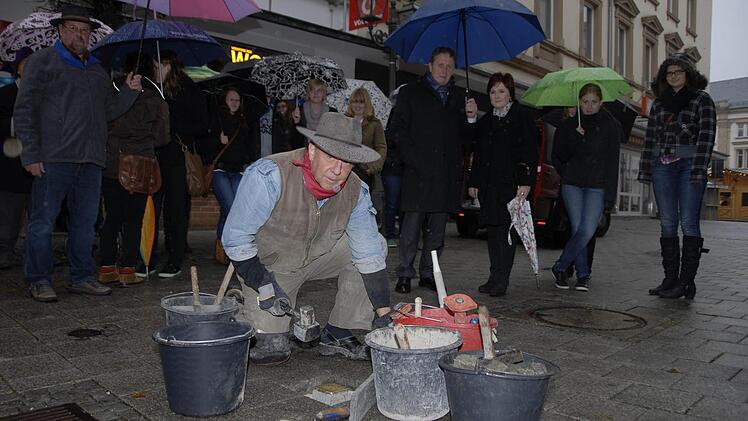 Der Kölner Bildhauer Gunter Demnig beim Verlegen früherer Stolpersteine