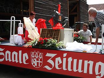 Roswitha Kaufmann, Lothar Metz und Jochem Schlick (von links) richten den Wagen für Rosenkönigin Anna-Lena Koch und Johannes Gutenberg (Lothar Metz) her.  Foto: Edgar Bartl