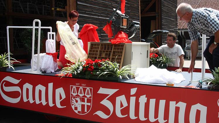 Roswitha Kaufmann, Lothar Metz und Jochem Schlick (von links) richten den Wagen für Rosenkönigin Anna-Lena Koch und Johannes Gutenberg (Lothar Metz) her.  Foto: Edgar Bartl
