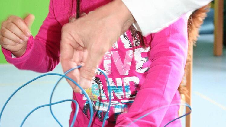 Andreia schließt mit den roten und schwarzen Bananensteckern den Stromkreis. Je mehr Batterien sie einsetzt, desto lauter wird der kleine Elektromotor.
