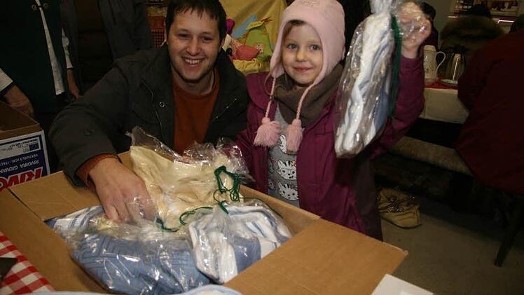 Elternbeiratsvorsitzender Sebastian Ott des Grafengehaiger Kindergartens und Franziska (5) wühlen in dem Karton mit selbstgenähten Turnsäckchen - und suchen sich das Schönste aus.