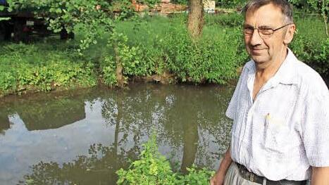 Rudolf Halbig steht am Mühlenkanal. Der ist zwar gefüllt, aber die Fließgeschwindigkeit ist durch die Trockenheit so niedrig, dass das Wasserkraftwerk viel weniger Strom als üblich produziert.  Foto: Heike Beudert