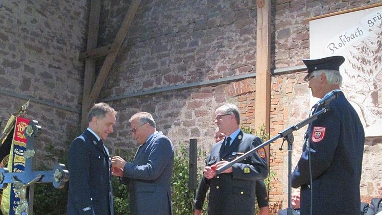 Rudi Leuber erhält die Ehrennadel von Emil Müller angesteckt, rechts daneben Kreisbrandinspektor Marco Brust. Foto: Diana Leitsch