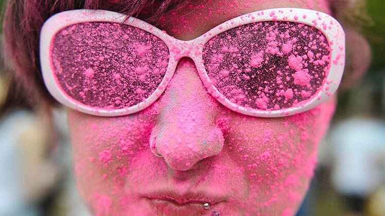 Eine Besucherin des Holi-Festival of Colours posiert am 11.05.2013 im Reiterstadion in Berlin mit buntem Pulver "geschminktem" Gesicht.  Foto: Ole Spata/dpa
