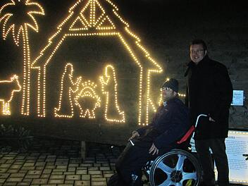 Werkstattleiter Thomas Porkristl zeigt einem Rollstuhlfahrer die von der Lebenshilfe erarbeitete Weihnachtsgeschichte aus LED-Lichtern.Winfried Ehling