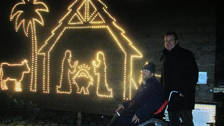 Werkstattleiter Thomas Porkristl zeigt einem Rollstuhlfahrer die von der Lebenshilfe erarbeitete Weihnachtsgeschichte aus LED-Lichtern.Winfried Ehling