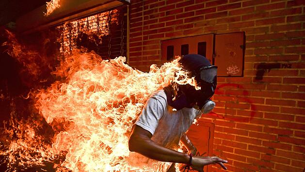 Jos&eacute; V&iacute;ctor Salazar Balza f&auml;ngt bei Auseinandersetzungen mit der Polizei, w&auml;hrend einer Demonstration gegen Venezuelas President Maduro, Feuer. Das Bild wurde als Weltpresse-Foto des Jahres 2018 ausgezeichnet. Foto: Ronaldo Schemidt/WORLD PRESS PHOTO/AFP/KEYSTONE/dpa