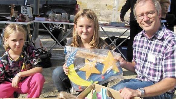 Chantal und Celina packen ihr Spielzeug vom Flohmarktstand ein und geben es an Peter Schubert, der es wiederum an syrische Flüchtlingskinder weitergeben soll.  Fotos: Hermann Fechter