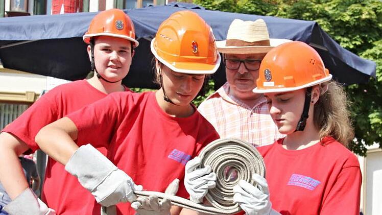 Feuerwehrhelm und Strohhut. Bei brütender Hitze war der Strohhutträger am Marktplatz, der den Feuerwehrnachwuchs aus Untermerzbach beim Aufrollen eines Schlauches über die Schulter schaut, eindeutig in der besseren Lage.  Fotos: Helmut Will