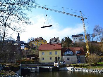 Mit einem schweren Autokran wurden die Einzelteile für die neue Wehrklappe über die frühere Trebgaster Mühle an den Weißen Main gehievt. Foto: Dieter Hübner