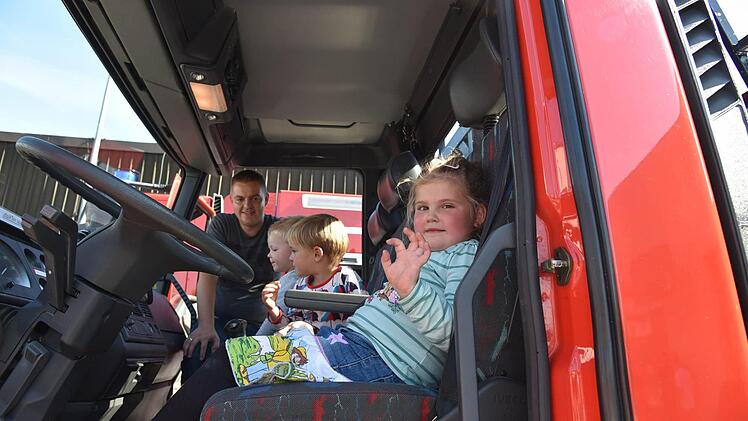 Vor allem die roten Fahrzeuge kamen bei den kleinen Besuchern super an. Torsten Schirmer aus Ahorn besichtigt mit den Kindern Ole, Felix und Emma ein Führerhaus. Foto: Gabi Arnold