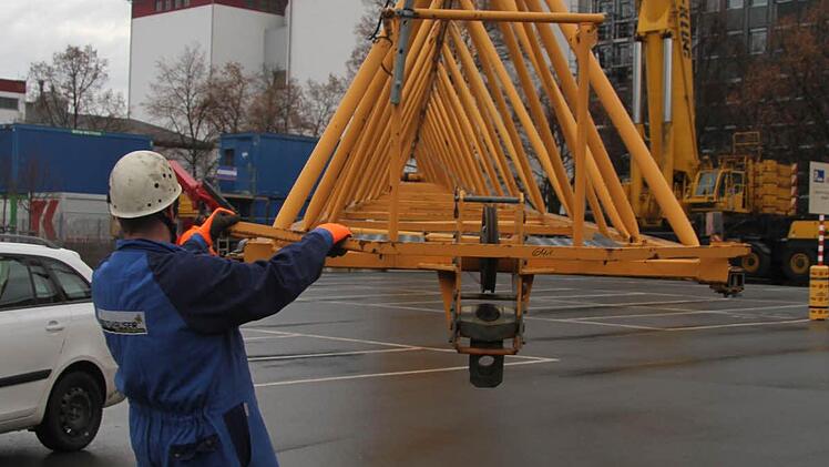 Jens Kronika und die anderen Mitarbeiter der Firma Beutlhauser gehen mit Routine ans Werk. Mit Seilen und purer Muskelkraft dirigieren sie den mächtigen Ausleger genau in die richtige Position. Und am Boden wird der Ausleger dann auseinandergenommen. Auch der Kranturm verschwindet bis zum Wochenende