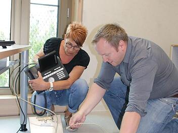 Jürgen Bischoff, Leiter Hauptverwaltung und IT, stöpselt mit seiner Kollegin Brigitte Reinhard das Telefon in seinem neuen Büro an. Die Techniker zogen als erstes um, um alles zu testen. Foto: Ralf Ruppert