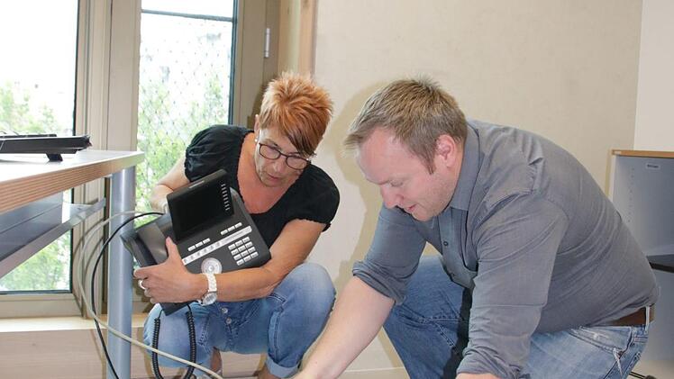 Jürgen Bischoff, Leiter Hauptverwaltung und IT, stöpselt mit seiner Kollegin Brigitte Reinhard das Telefon in seinem neuen Büro an. Die Techniker zogen als erstes um, um alles zu testen. Foto: Ralf Ruppert