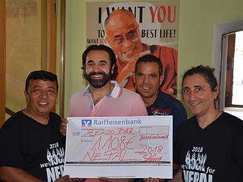 Spendenübergabe vor dem Plakat des Dalai Lama in  der Herzo Bar für Nepal:  Alberto Parmigiani (rechts)   und sein Mitstreiter Santa Ratna Shakya (links) freuen sich über den Scheck von Sami Alijaj (Zweiter von links). Mit auf dem Bild  dessen Helfer Sadi Foto: Bernhard Panzer