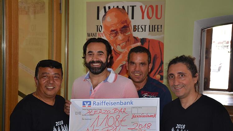 Spendenübergabe vor dem Plakat des Dalai Lama in  der Herzo Bar für Nepal:  Alberto Parmigiani (rechts)   und sein Mitstreiter Santa Ratna Shakya (links) freuen sich über den Scheck von Sami Alijaj (Zweiter von links). Mit auf dem Bild  dessen Helfer Sadi Foto: Bernhard Panzer